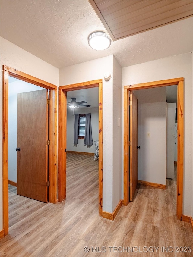 corridor with baseboards, a textured ceiling, and wood finished floors