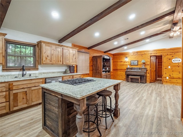 kitchen with light wood-type flooring, a sink, lofted ceiling with beams, wooden walls, and stainless steel appliances