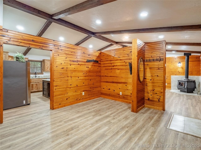 bonus room with wooden walls, lofted ceiling with beams, light wood finished floors, a wood stove, and recessed lighting