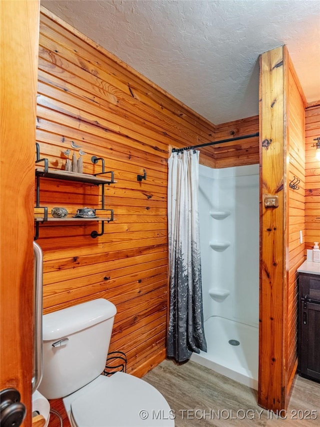 bathroom with wood walls, a textured ceiling, a shower with shower curtain, and toilet