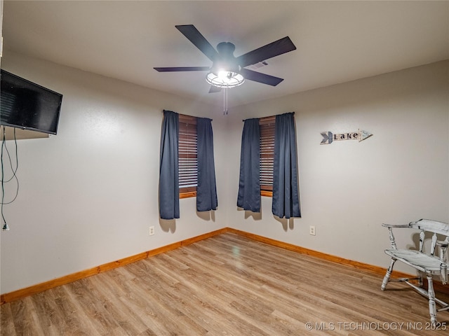spare room with baseboards, ceiling fan, wood finished floors, and visible vents