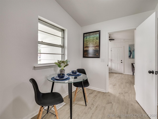dining area with baseboards, vaulted ceiling, and light wood-type flooring
