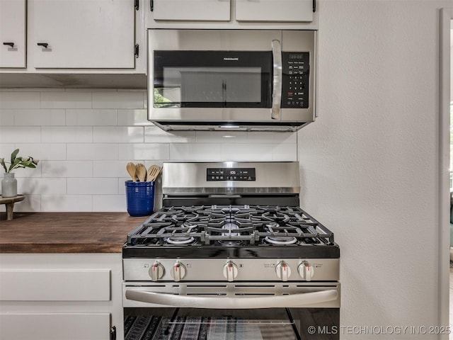 kitchen with backsplash, white cabinets, appliances with stainless steel finishes, and butcher block counters