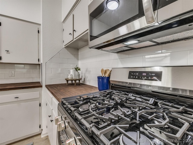 kitchen with appliances with stainless steel finishes, decorative backsplash, wooden counters, and white cabinets