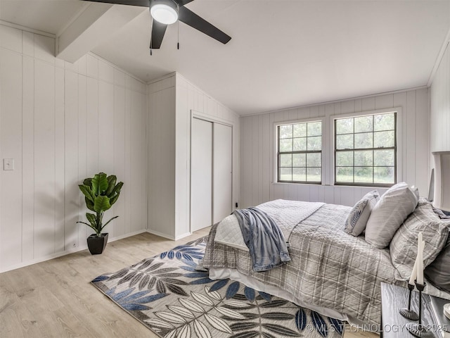 bedroom with a closet, light wood-style floors, baseboards, ceiling fan, and vaulted ceiling with beams