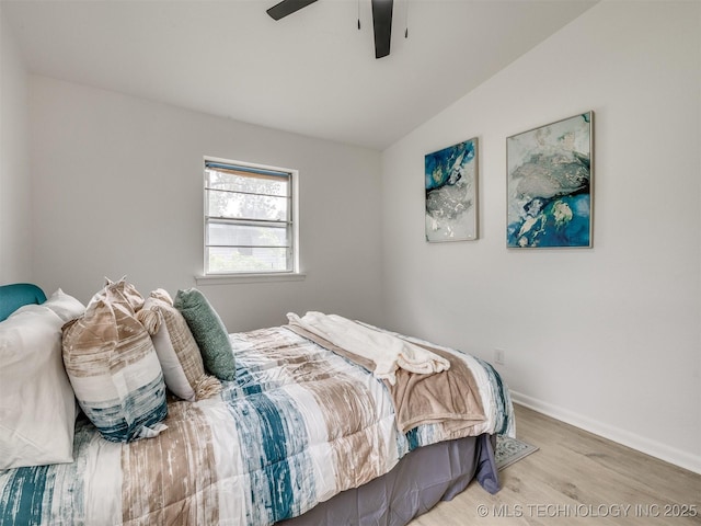 bedroom with baseboards, a ceiling fan, wood finished floors, and lofted ceiling