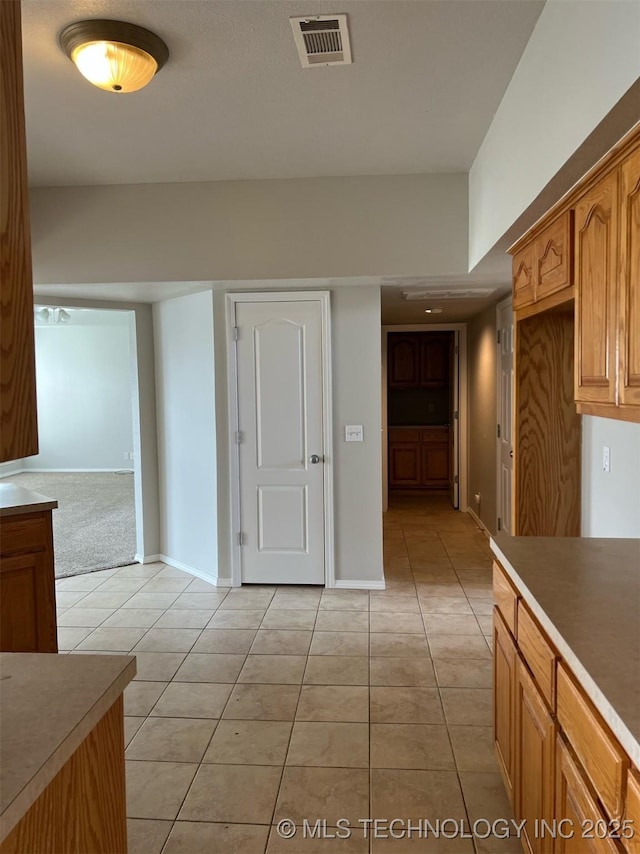 kitchen with light countertops, visible vents, brown cabinetry, and light tile patterned floors