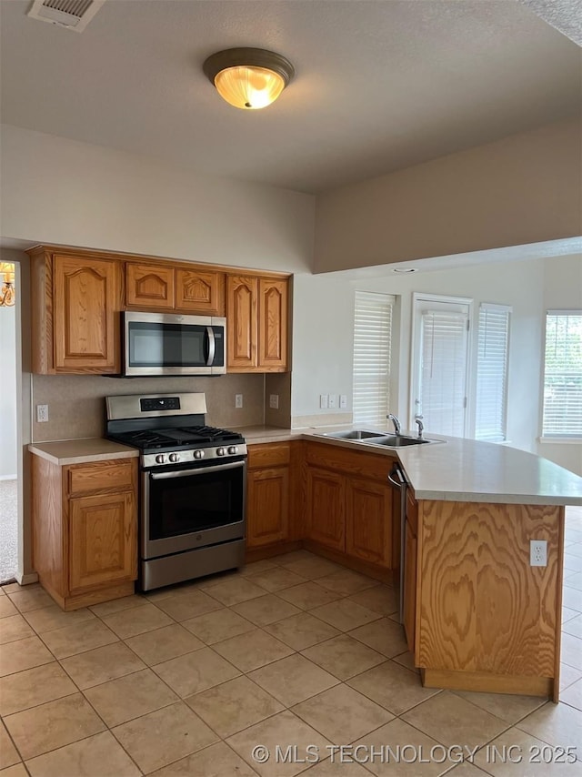 kitchen with light countertops, light tile patterned flooring, appliances with stainless steel finishes, and a sink