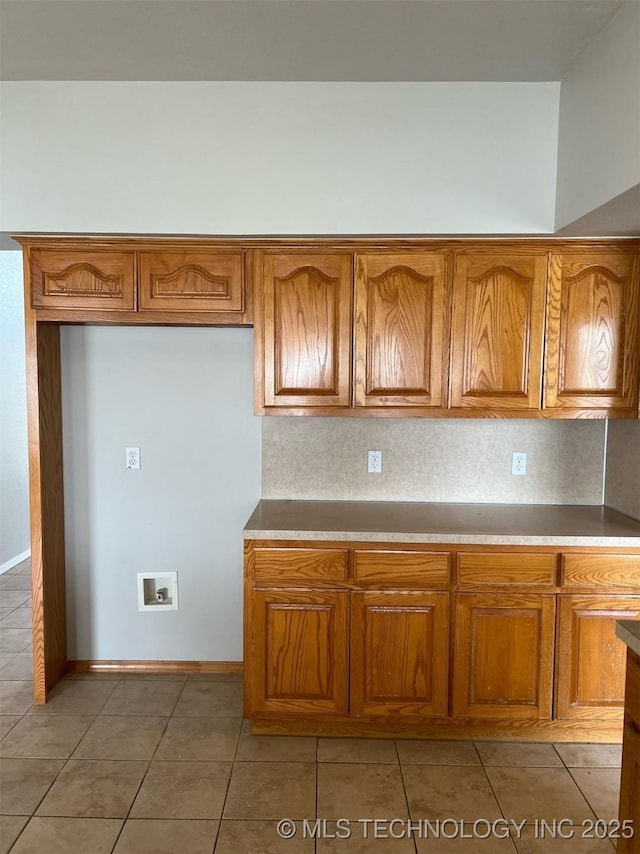 kitchen with baseboards, light tile patterned floors, and brown cabinets