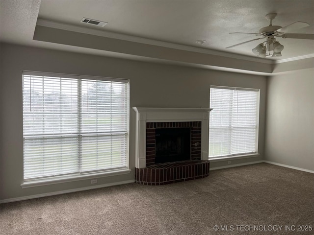 unfurnished living room featuring a ceiling fan, carpet, a tray ceiling, and visible vents