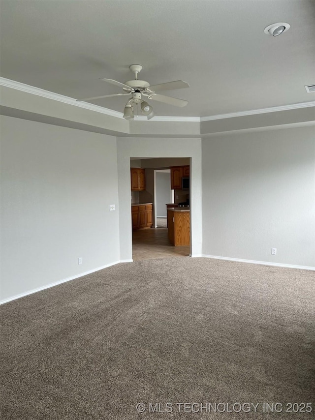 carpeted spare room with baseboards, ornamental molding, a ceiling fan, and visible vents
