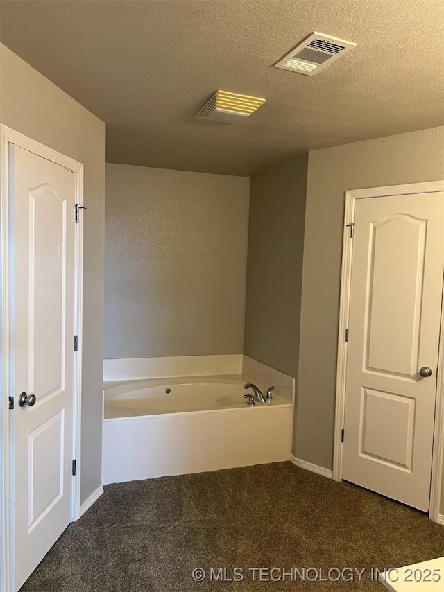 bathroom with carpet floors, a garden tub, a textured ceiling, and visible vents