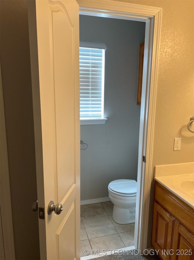 bathroom with vanity, tile patterned flooring, baseboards, and toilet