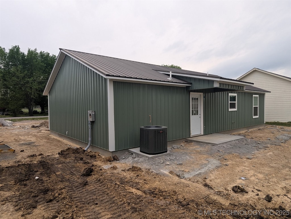 back of property featuring central air condition unit and metal roof