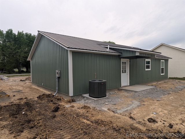 back of property featuring central air condition unit and metal roof
