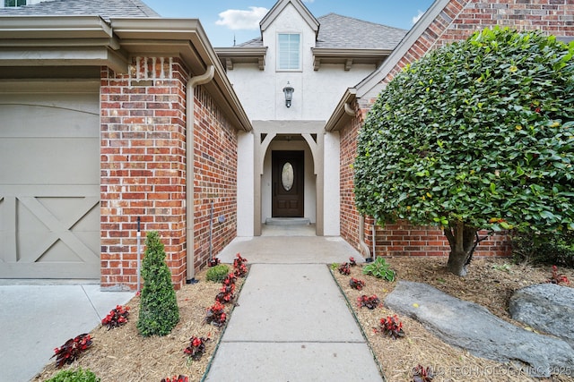 doorway to property with brick siding, a shingled roof, and an attached garage