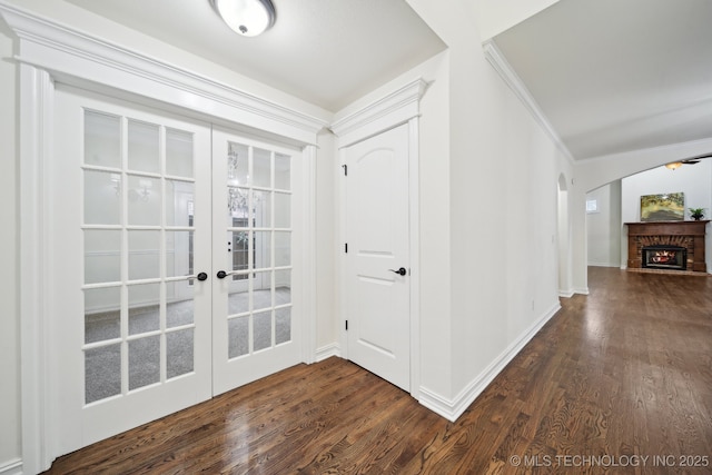 foyer featuring french doors, dark wood-style flooring, ornamental molding, baseboards, and arched walkways