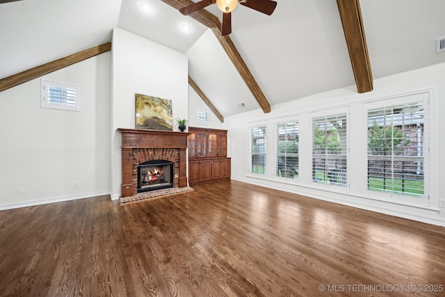 unfurnished living room featuring a ceiling fan, a fireplace, beam ceiling, wood finished floors, and high vaulted ceiling