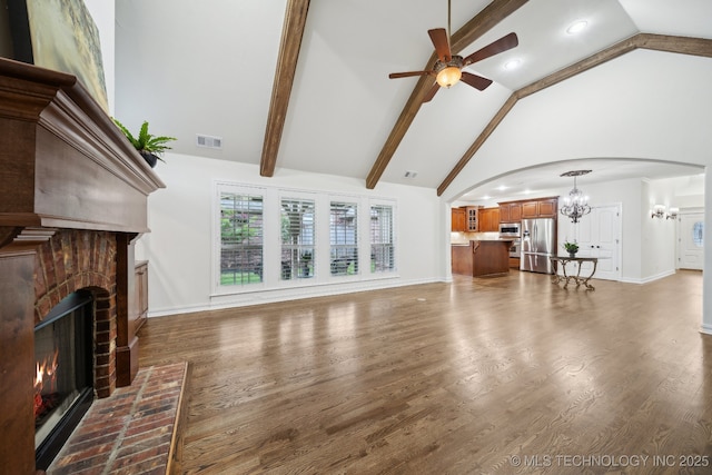 living room with a chandelier, arched walkways, a ceiling fan, a brick fireplace, and high vaulted ceiling