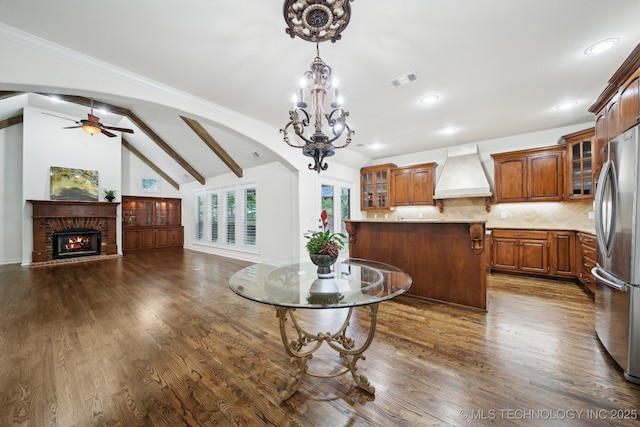 kitchen featuring premium range hood, freestanding refrigerator, lofted ceiling, dark wood finished floors, and a peninsula