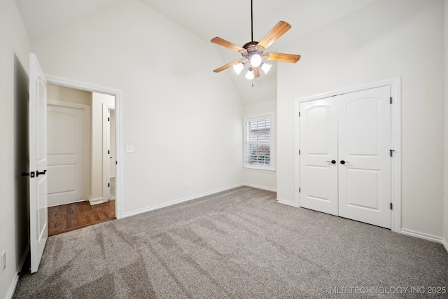 unfurnished bedroom with high vaulted ceiling, carpet, baseboards, a closet, and a ceiling fan