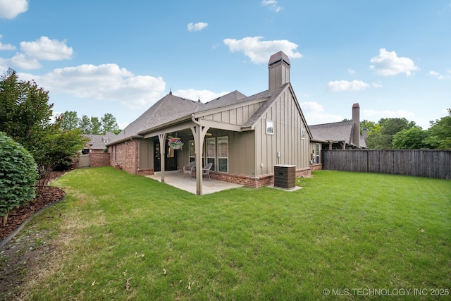 rear view of house featuring board and batten siding, a patio, a chimney, roof with shingles, and brick siding