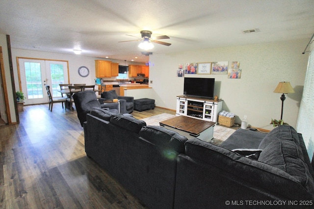 living area featuring a ceiling fan, baseboards, visible vents, and wood finished floors