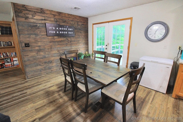 dining area featuring a textured ceiling, french doors, wood finished floors, and visible vents
