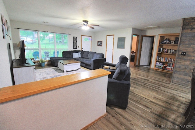 living room featuring a ceiling fan, a textured ceiling, and wood finished floors