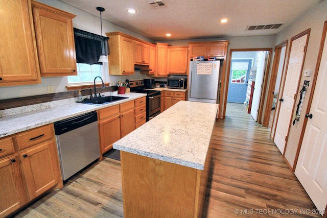 kitchen with visible vents, under cabinet range hood, a sink, light wood finished floors, and stainless steel appliances