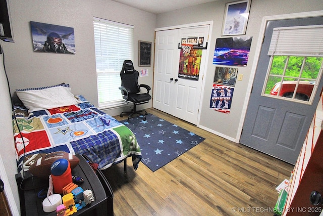 bedroom with baseboards, wood finished floors, and multiple windows