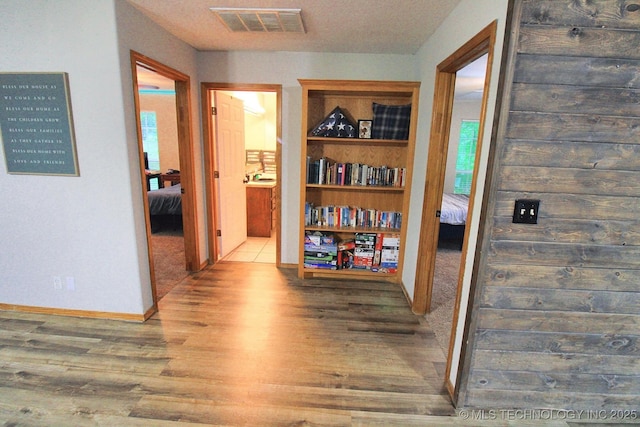 hallway featuring baseboards, wood finished floors, and visible vents