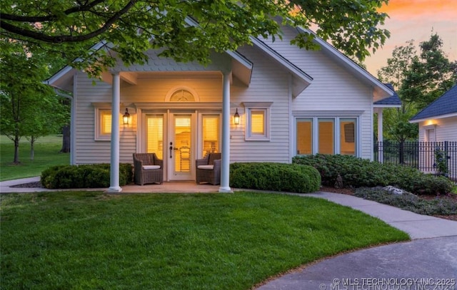 back of property with a yard, fence, and a porch