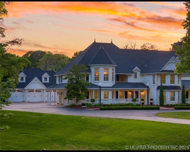 view of front of house featuring a lawn, a garage, driveway, and covered porch