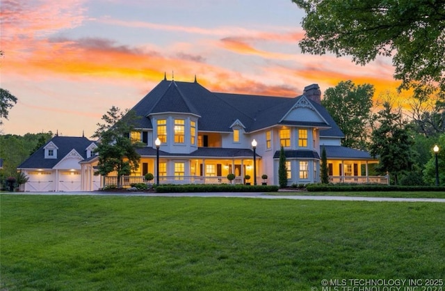 back of house at dusk with a lawn, a chimney, a gate, and a garage