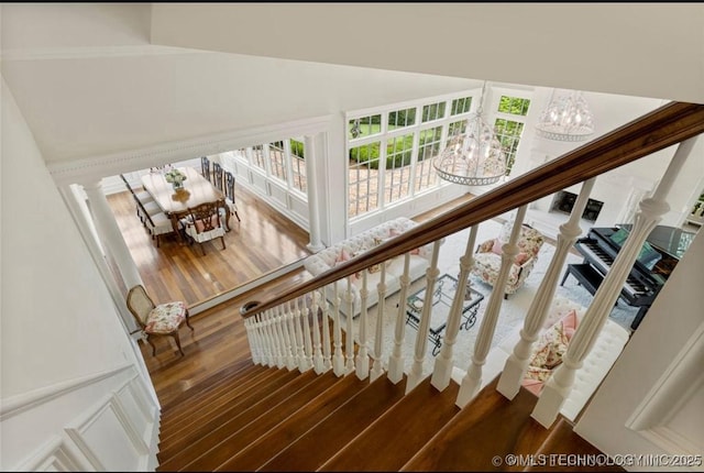 stairs featuring a towering ceiling, wood finished floors, and a notable chandelier