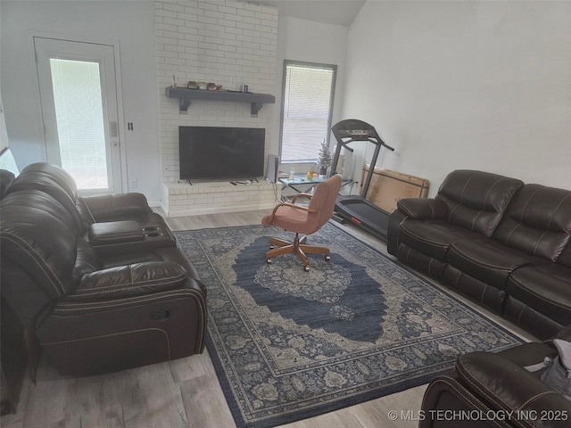 living area featuring a brick fireplace and wood finished floors