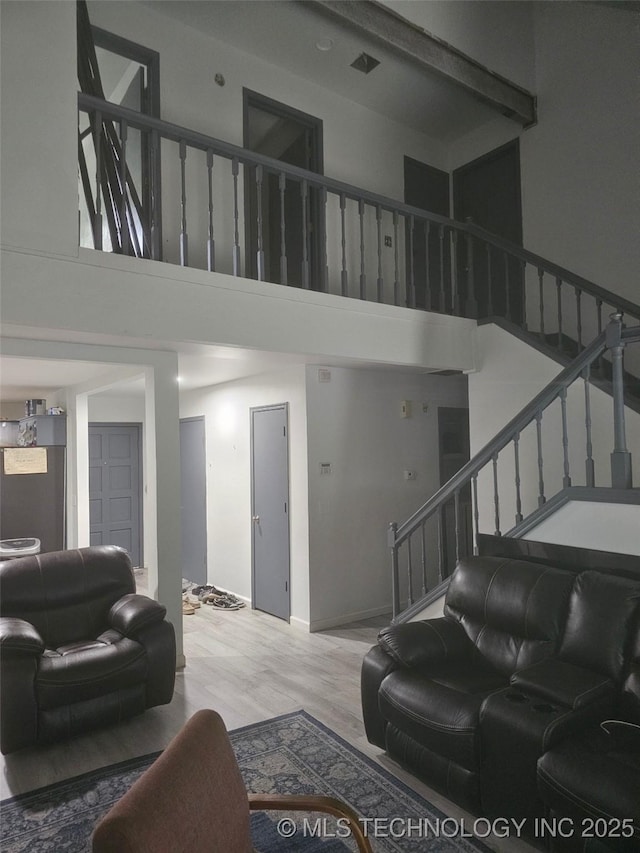 living room with baseboards, a high ceiling, wood finished floors, and stairway