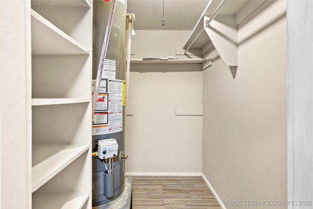 walk in closet with wood finished floors and water heater