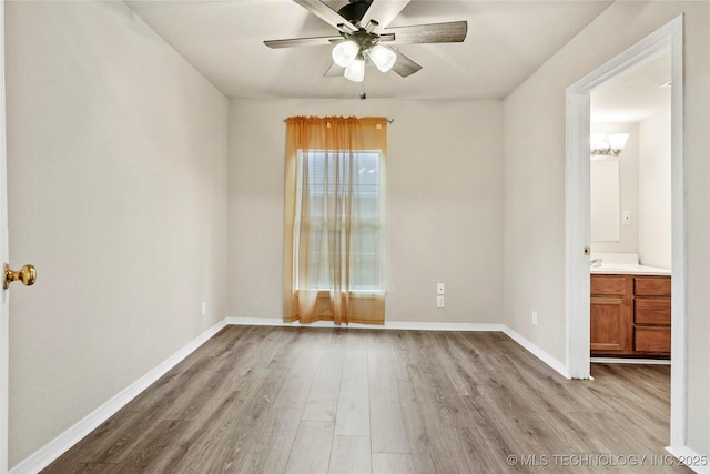 unfurnished bedroom featuring connected bathroom, baseboards, and wood finished floors