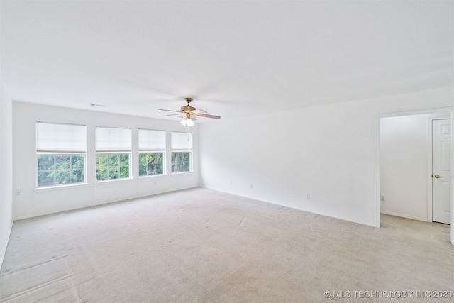 empty room featuring light colored carpet, a ceiling fan, baseboards, and visible vents