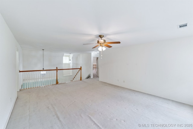 empty room featuring visible vents, carpet flooring, and ceiling fan