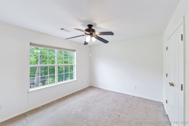 unfurnished room featuring baseboards, a ceiling fan, light colored carpet, and visible vents