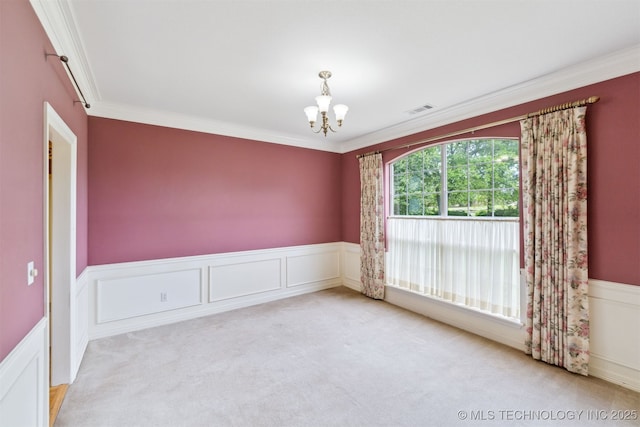 spare room featuring crown molding, a chandelier, carpet, a wainscoted wall, and visible vents