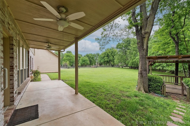 view of yard featuring fence, a ceiling fan, and a patio area