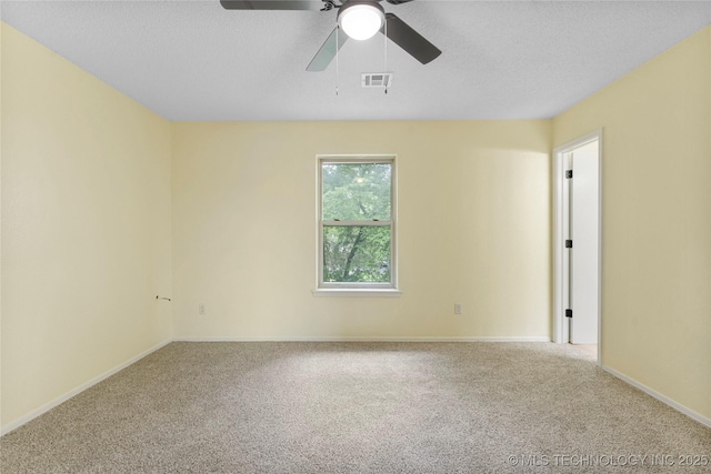 carpeted empty room with visible vents, a textured ceiling, baseboards, and ceiling fan