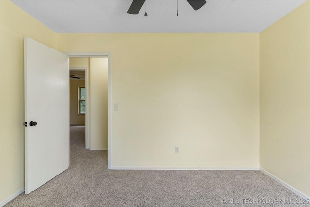 spare room with baseboards, a ceiling fan, and light colored carpet