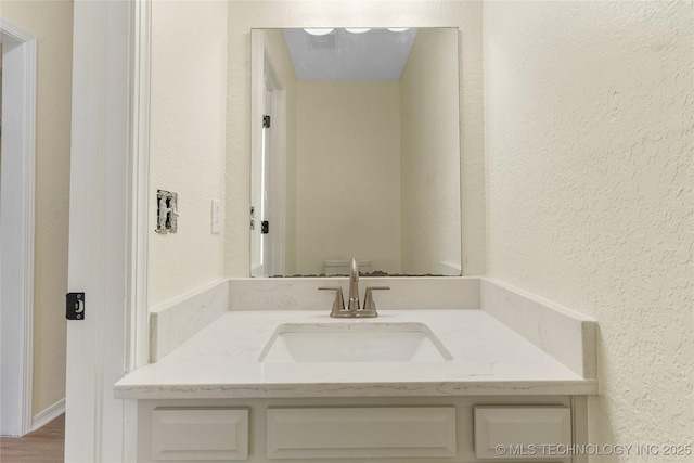 bathroom with a textured wall and vanity
