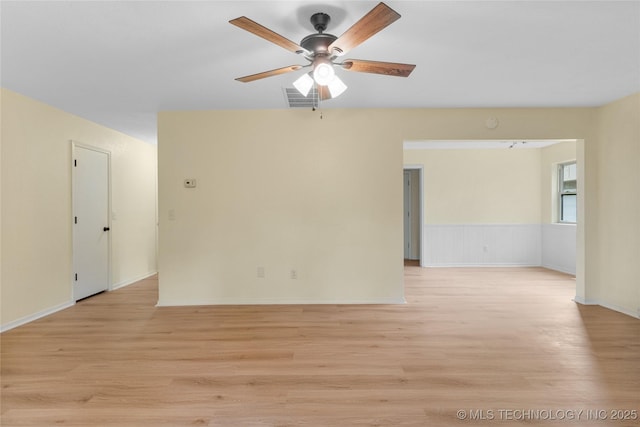 spare room with light wood-type flooring, baseboards, ceiling fan, and visible vents