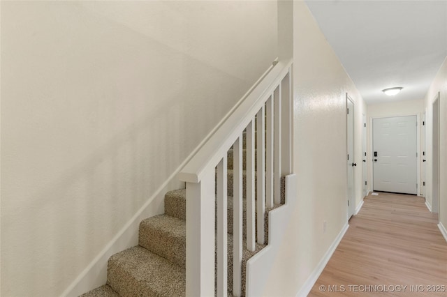 stairway featuring baseboards and wood finished floors